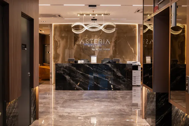 Dark stone reception counter under the Asteria Melaka signage.