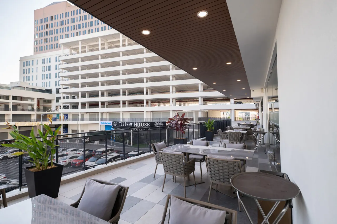 Alfresco terrace above the retail deck at Asteria Melaka, tables set under a timber soffit.